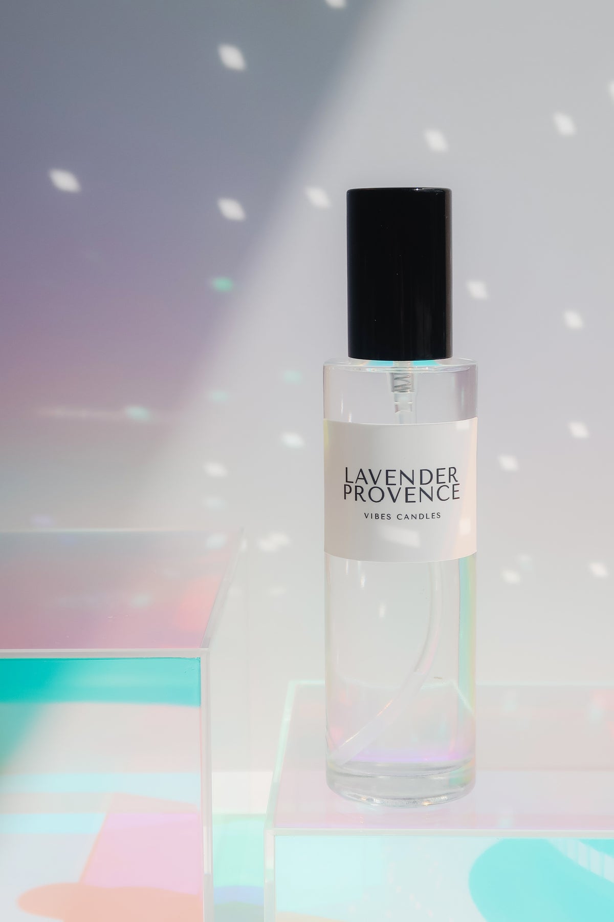 Lavender Provence room spray in a glass container with a black lid on a iridescent background.